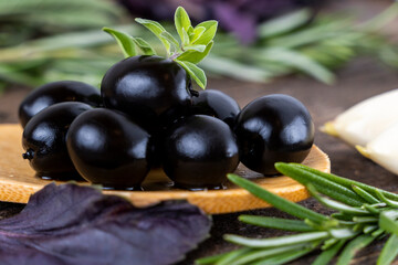 olives with spices and rosemary in a wooden spoon