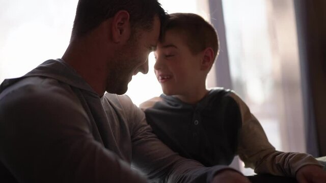 A father and son sit on the sofa at home
