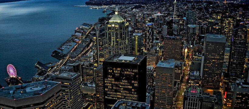 An Aerial Panorama Of Seattle, Washington Looking North At Dusk With The Space Needle In The Distance And The Ferris Wheel Lite Up In The Lower Left.