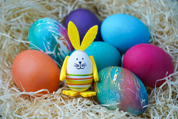 Fototapeta na wymiar Easter eggs in the nest with cute bunny shaped easter ornament