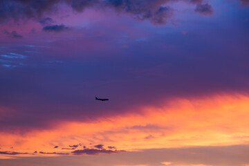 Horizontal view of plane flying above sunset with dramatic coloured sky, Montreal, Quebec, Canada