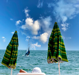 Two sun loungers and a sailboat on the sea