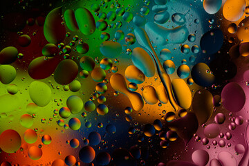 bright colorful oily drops in water with colorful background, close-up 