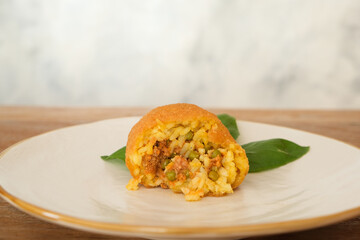 Fried arancino ball meat sauce peas and basil, traditional italian food