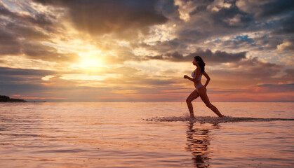 Fototapeta na wymiar Young beautiful sexy fit lingerie brunette model running in the water at dramatic sunset 
