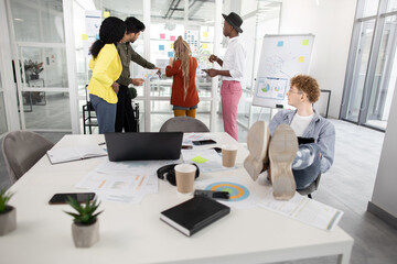 Diverse people brainstorming about common startup project near glass wall with stickers