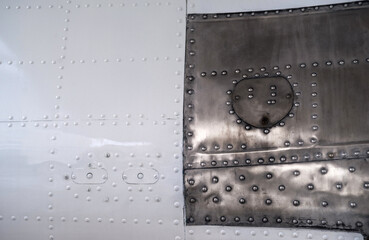 Metal surface texture with rivets, partially painted in white.