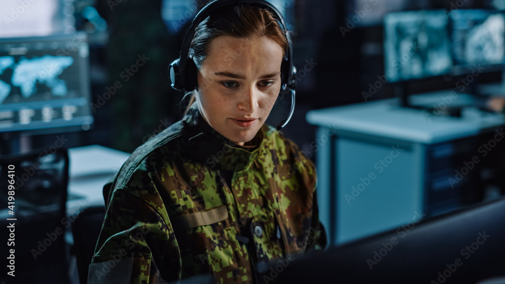 Poster beautiful female military surveillance officer in headset working in central office hub for cyber op