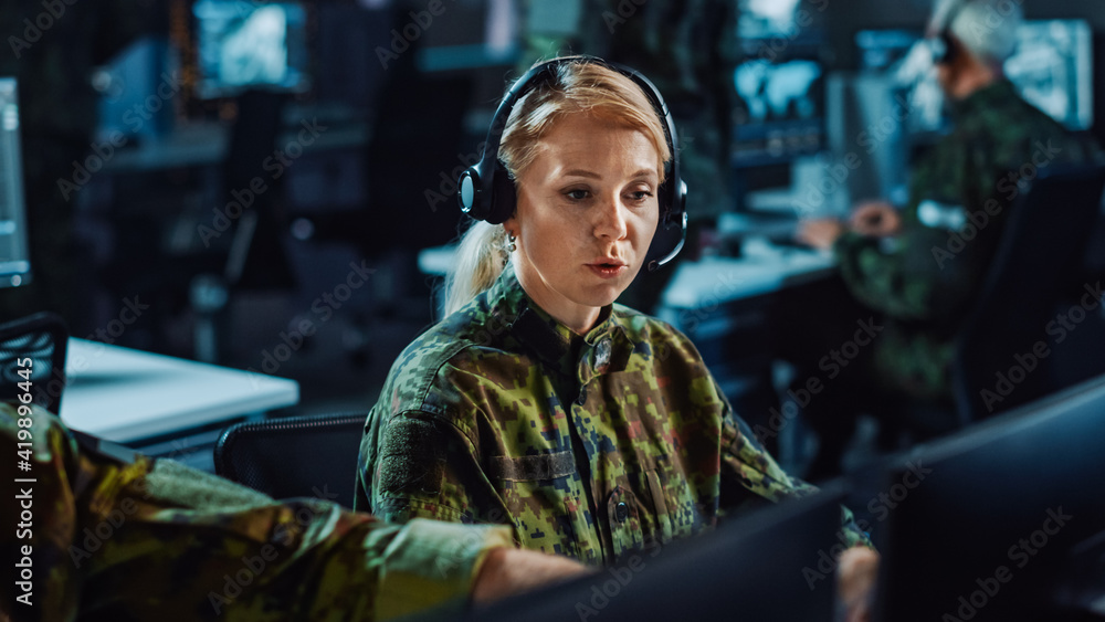 Poster beautiful female military surveillance officer in headset working in central office hub for cyber op