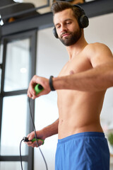 Fototapeta na wymiar Athletic young man in headphones looking at his fitness tracker