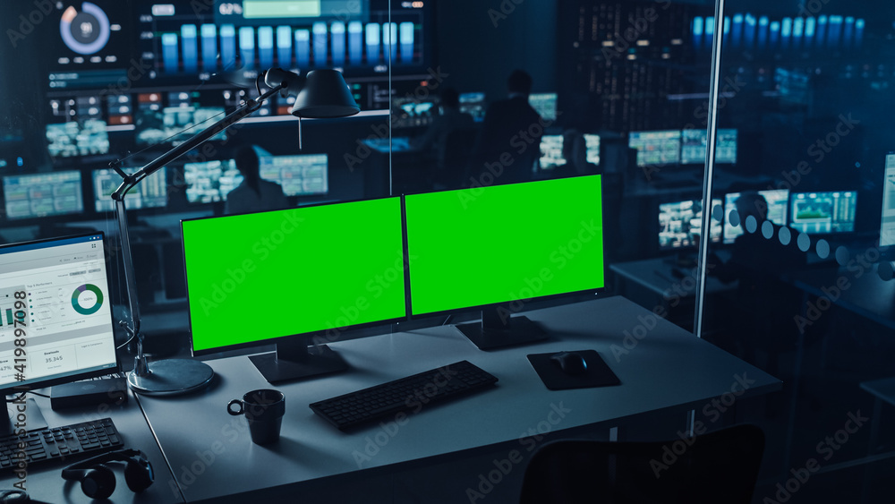 Aufkleber Two Digital Computer Screens with a Green Mock Up Chromakey in Modern Monitoring Office. Control Room with Specialists and Managers Sit in Front of Computers. 