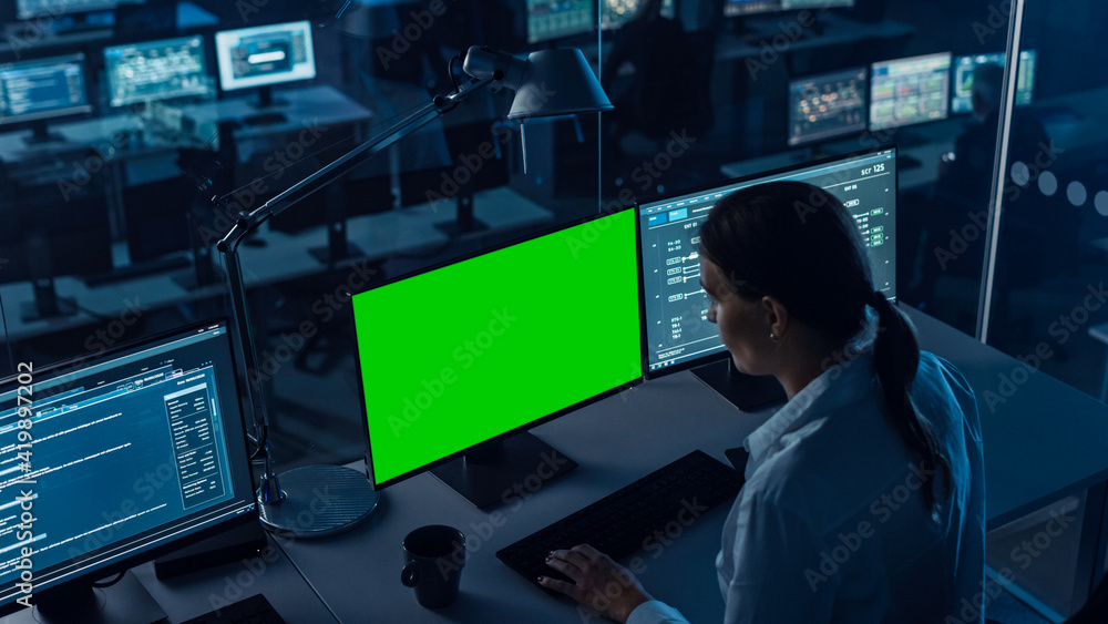 Poster Female Software Engineer Working in a Modern Monitoring Office with Green Screen Mock Up on a Computer Display. Monitoring Room Big Data Scientists and Managers Sit in Front of Computers.