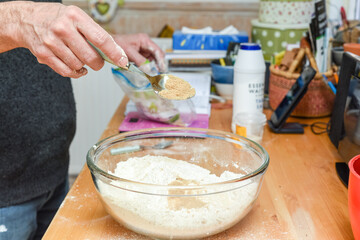 Person making bread in home kitchen adding ingredients to make the dough