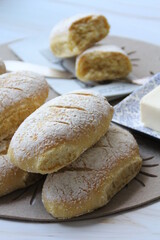 fresh cornmeal buns, butter on a plate, flour-sprinkled buns, fresh bread, homemade baked goods