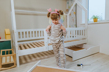 Little girl in pajamas and butterfly costume play in bedroom