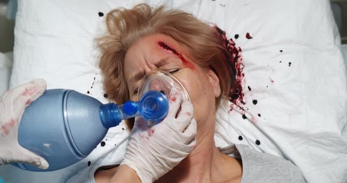 Top view of medic worker using valve mask bag on injured aged woman