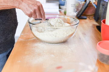 Person making bread in home kitchen adding ingredients to make the dough