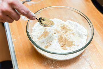 Person making bread in home kitchen adding ingredients to make the dough