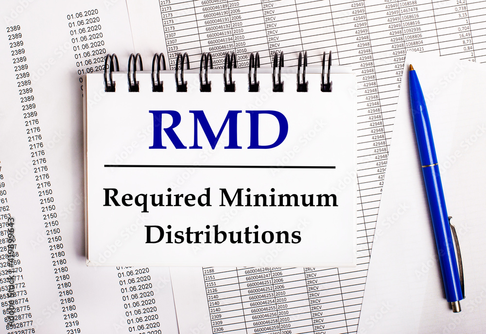 Poster on the table are charts and reports, on which lie a blue pen and a notebook with the word rmd requir