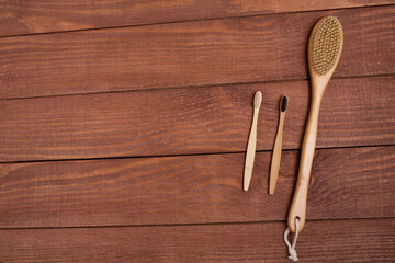 Eco-friendly bath products. Wooden natural body massage brush and bamboo natural toothbrushes on the wooden background.
