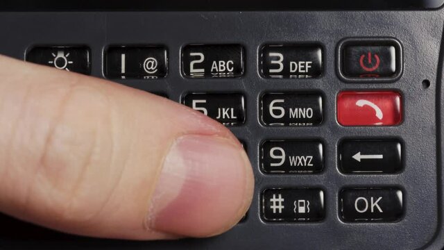 Male hands presses on the black old buttons of a mobile phone, close-up.