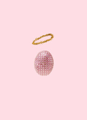 Easter concept. Sparkling disco egg with helo. Pastel pink background.
