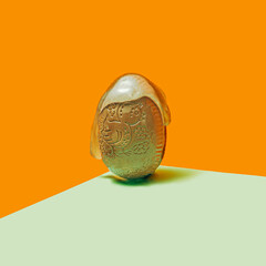 Easter concept. Chocolate  egg with slime. Orange and green background.