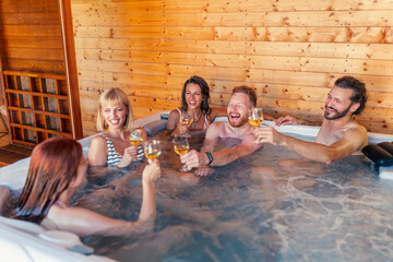 Friends making a toast and relaxing in a hot tub while on a vacation