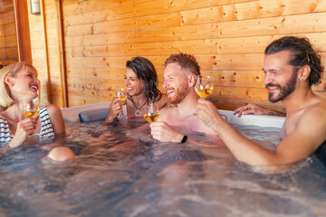Friends drinking wine and relaxing in a hot tub while on a vacation