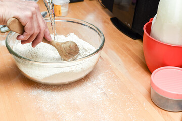 Person making bread in home kitchen adding ingredients to make the dough