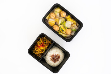 Top view of spicy curry pork with rice and meat ball vegetable soup in black contain box.