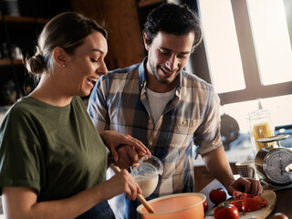 Husband and wife in kitchen. Young couple preparing delicious food at home.