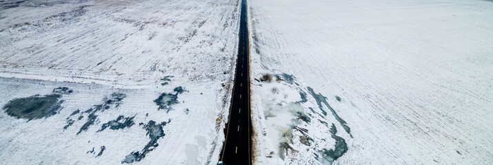Top view from the air on the winter road in the field on which cars are going. Space for text. Travel concept.