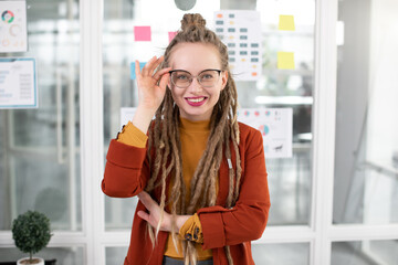 Close up portrait of young smiling woman with dreadlocks posing at office