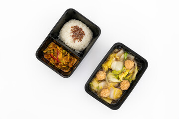 Top view of spicy curry pork with rice and meat ball vegetable soup in black contain box. Isolate in white.