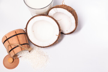 opened coconut near coconut flakes in wooden bowl and glass of coconut milk isolated on white background. tropical, nut. coco.
