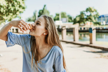 Outdoor lifestyle portrait of young trendy girl eating ice cream in summer hot sunny day in street city