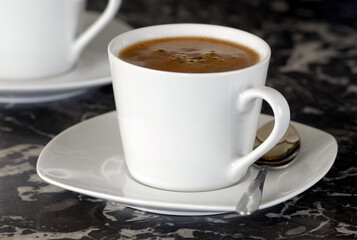 weiße Kaffeetasse mit Löffel auf Marmorplatte