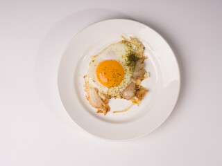 Fried eggs on a white round plate. Studio photo on white background