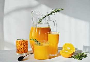 raw sea buckthorn and orange juice in glasses. with rosemary. antioxidant drinkfor immunity boost...