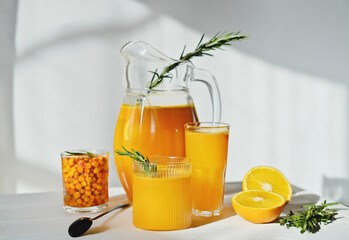raw sea buckthorn and orange juice in glasses. with rosemary. antioxidant drinkfor immunity boost in spring. vitamin juice for healthy life