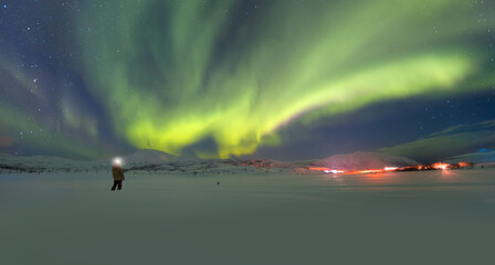 A man illuminates the sky with the lantern - Northern lights or Aurora borealis in the sky with  - Tromso, Norway