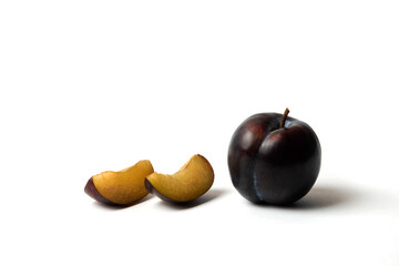 Whole and sliced black cherry plums on white background
