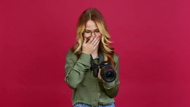 Young blonde girl photographer smiling a lot while covering mouth over isolated background