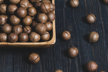macadamia nuts in a wooden bowl close up on a dark background