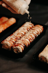 The chef sprinkles sesame seeds on a take-away sushi set © alexblackphoto
