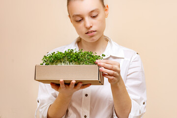 vegetarian woman holding an eco box made of organic micrograms of mustard sprouts. Growing sprouts....