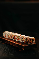 Close-up of sushi with salmon and avocado on a wooden cutting board