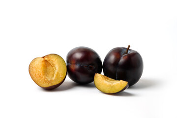 Whole and sliced black cherry plums on white background