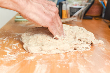 Person making bread in home kitchen adding ingredients to make the dough